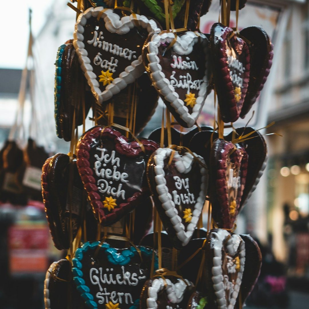 Herzförmige Lebkuchenplätzchen mit bunten Schriftzügen und Verzierungen.